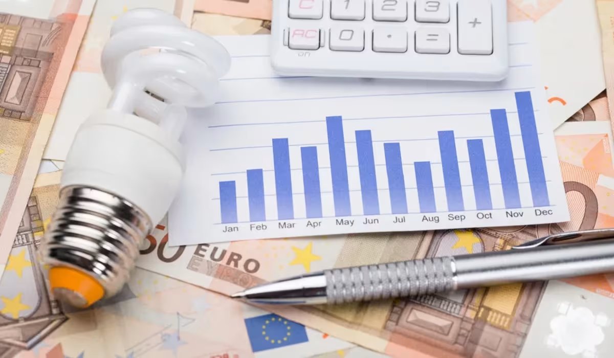 Lampadina a risparmio energetico, banconote e grafico dei consumi mensili